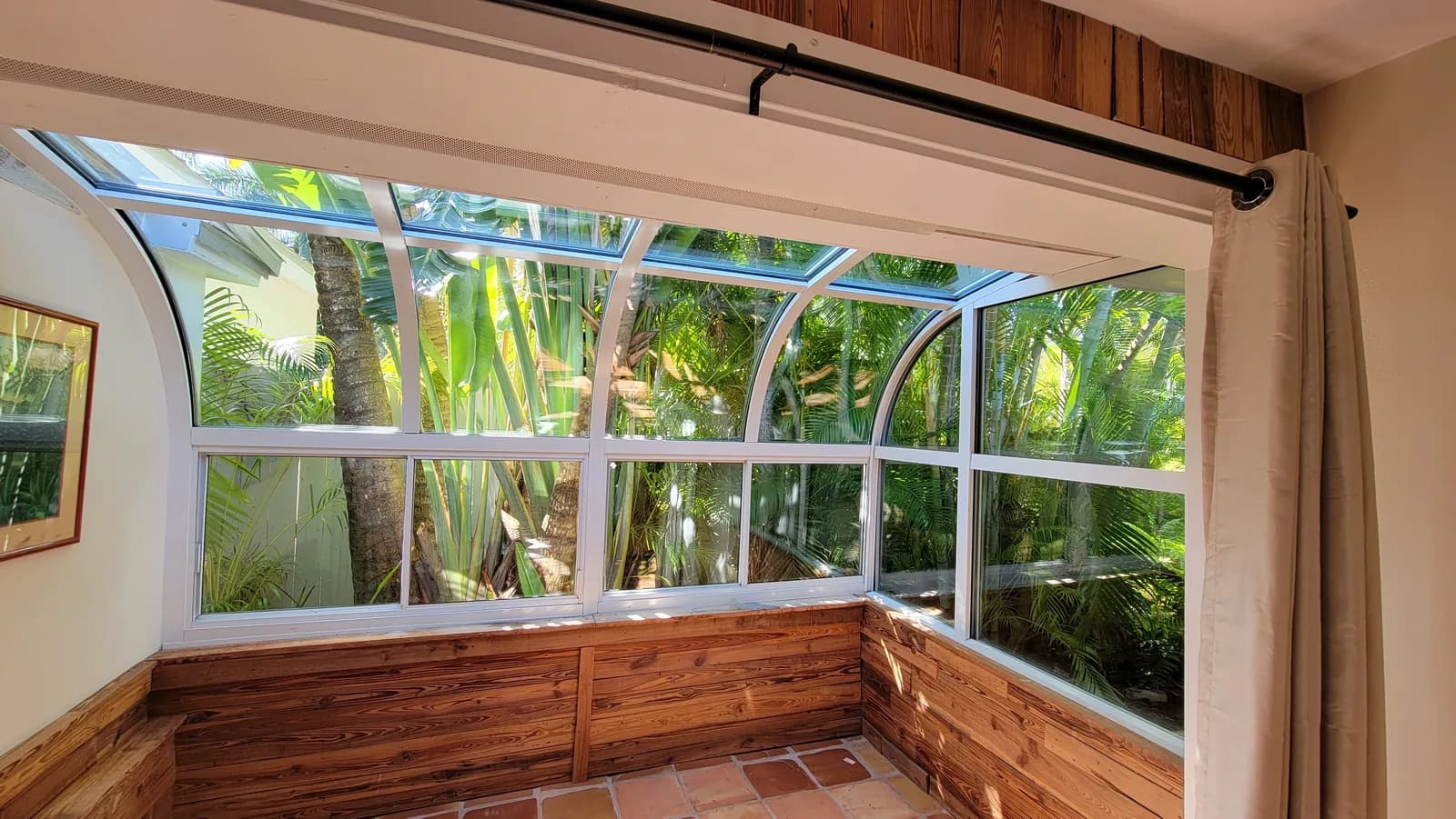 Spotless sunroom windows looking out onto tropical palms after professional cleaning