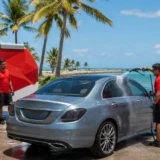 Leoserve team car detailing in Marathon FL with red shirts and red-white truck near turquoise water.