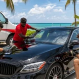 ceramic coating Key West — LeoServe team in red shirts applying ceramic coating to a vehicle with a red and white truck in background, Florida Keys tropical setting
